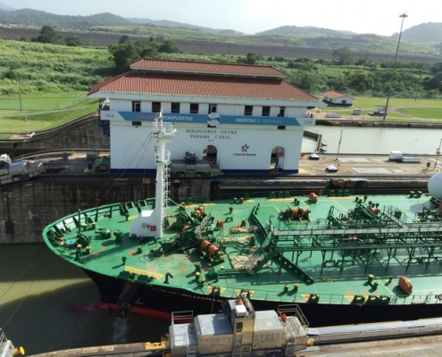 Ship passing through Panama's Miraflores Lock with Visitor Center in the background