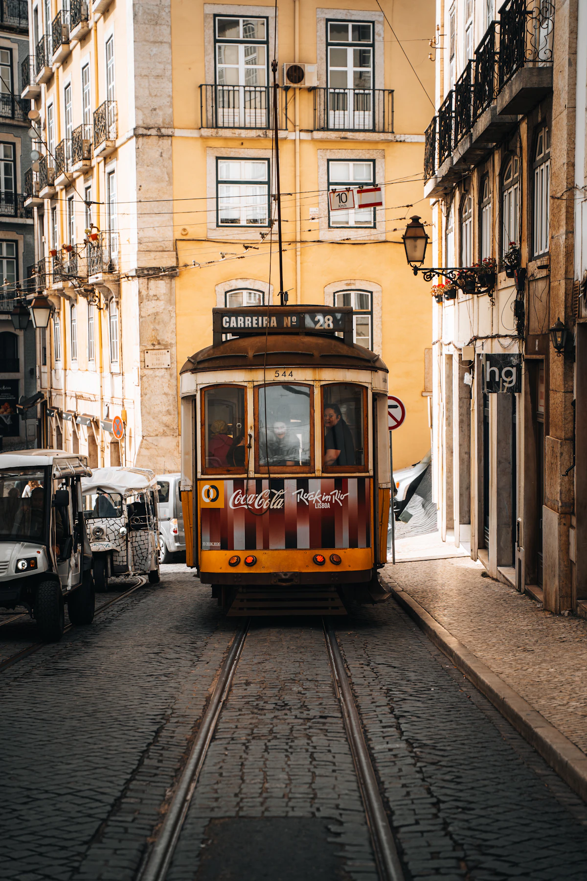 A yellow Tram 28 navigating the narrow streets of Lisbon's historic neighborhoods