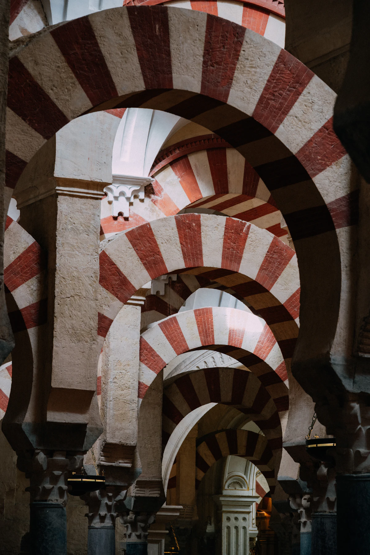 The iconic red and white horseshoe arches and marble columns inside the Mosque-Cathedral of Cordoba